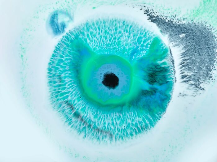 Hypnotic image resembling a human eye created by a photographer using ink and water swirling in blue tones.