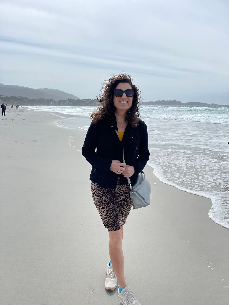 Woman smiling on a beach wearing sunglasses, leopard print skirt, and carrying a handbag, symbolizing campaign to find love. Woman smiling on a beach wearing sunglasses, leopard print skirt, and carrying a handbag, symbolizing campaign to find love.