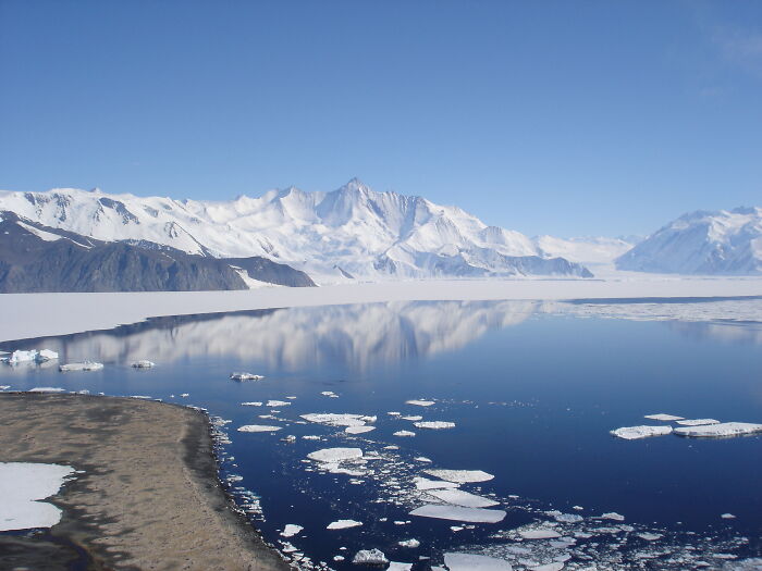 Snow-covered mountains and floating icebergs in a calm lake showcasing incredible weather records and nature’s powerful forces.