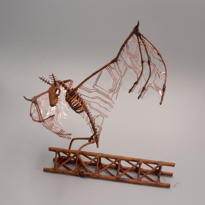 Haunting porcelain sculpture of a skeletal mythical creature with translucent patterned wings perched on a rusted metal base.