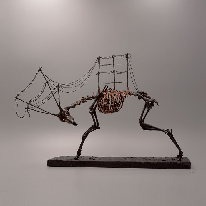 Skeletal porcelain sculpture resembling a mythical creature with wire details, evoking relics of forgotten myths in haunting art.