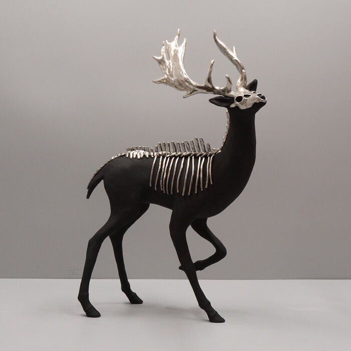 Black porcelain sculpture of a deer with silver antlers and skeletal details, evoking haunting relics of forgotten myths.