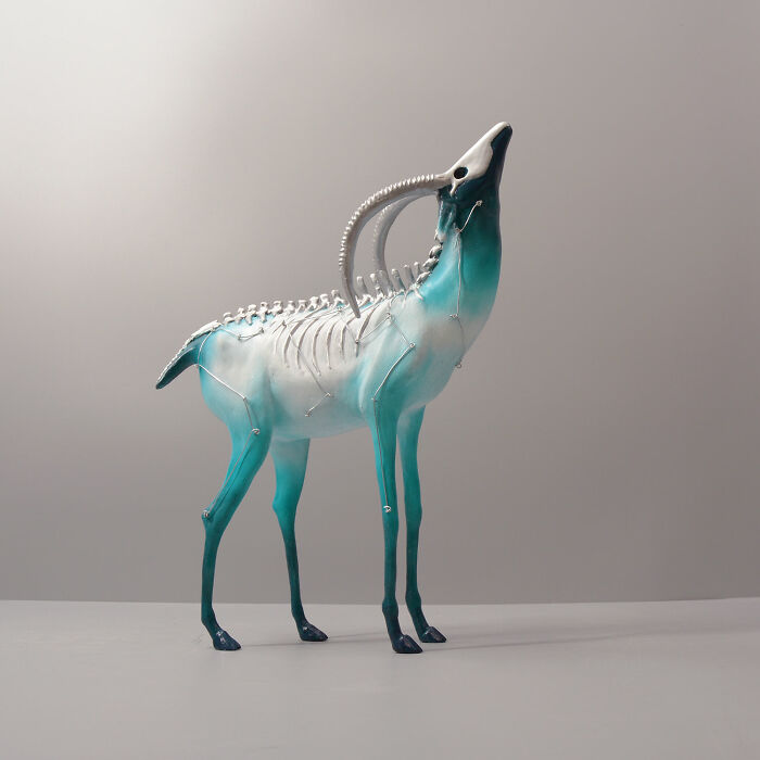 Porcelain sculpture of a mythical deer-like creature with exposed spine and ribs, blending blue and white shades.