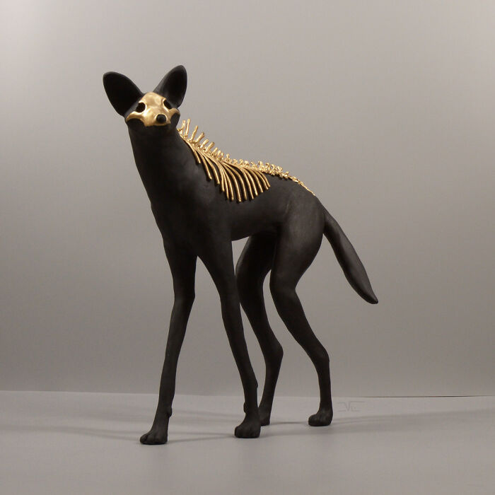 Porcelain sculpture of a black canine with gold skeletal details, evoking haunting relics of forgotten myths in art form.
