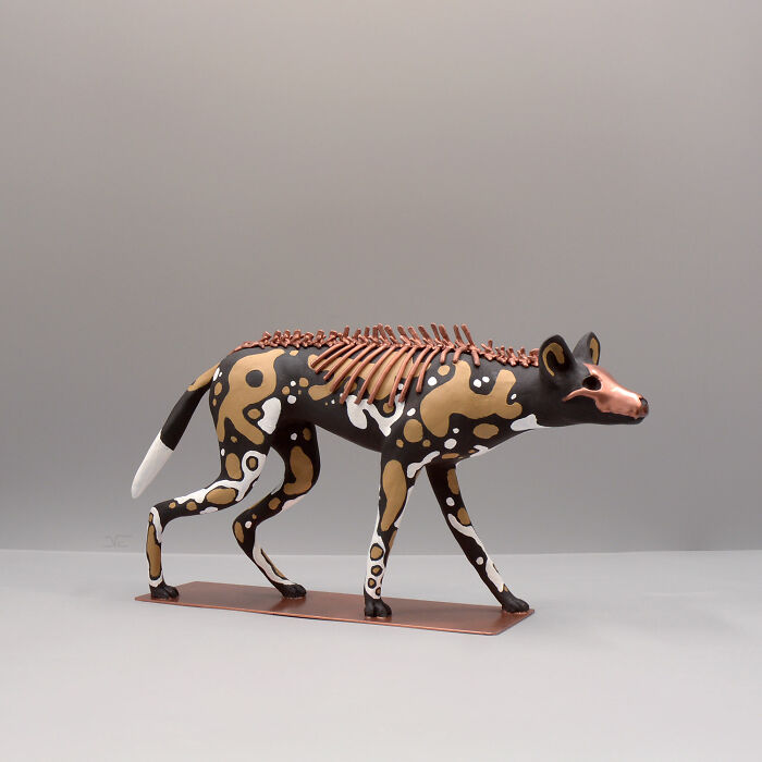 Porcelain sculpture of a patterned animal with metallic skeletal elements, resembling a haunting relic of forgotten myths.
