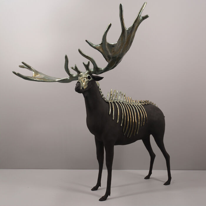 Porcelain sculpture of a haunting stag with metallic antlers and ribcage resembling relics of forgotten myths.