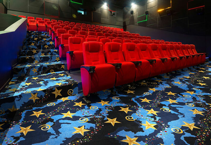 Empty movie theater with rows of red seats and a colorful patterned carpet evoking nostalgic images feeling.