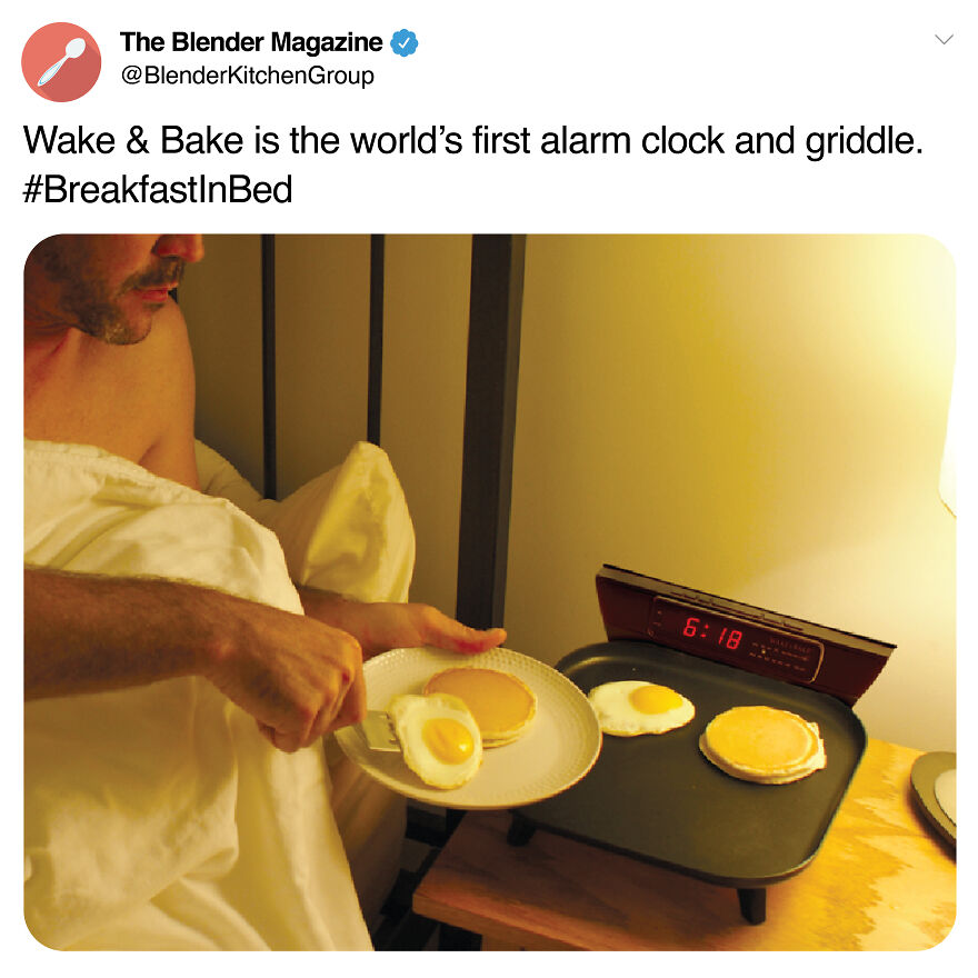 Man in bed using a prank alarm clock and griddle combo cooking pancakes and eggs on a breakfast tray.