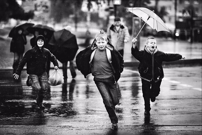 Children running and playing with umbrellas in the rain, capturing beautiful photos of childhood around the world.