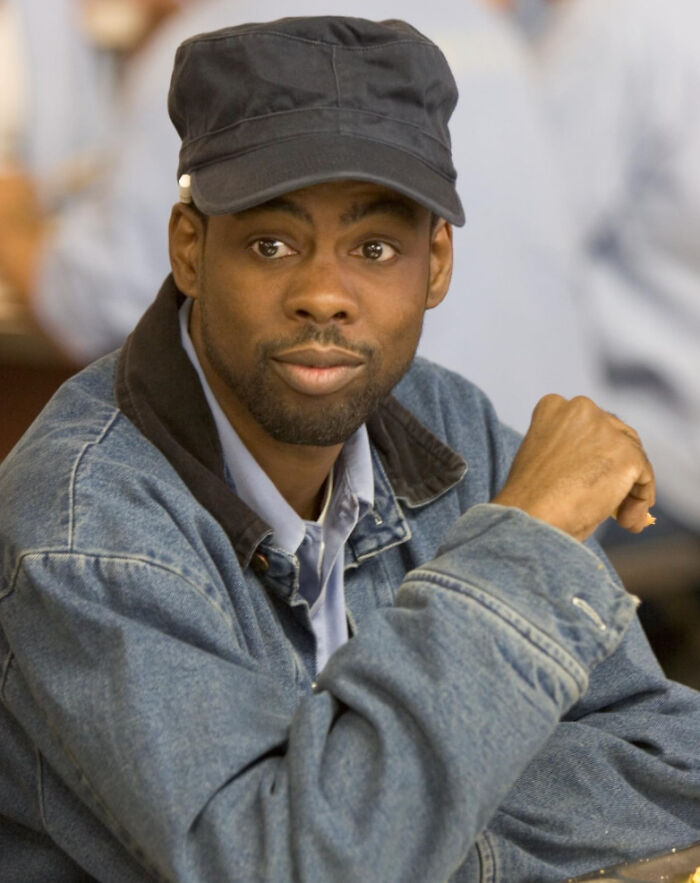 Man wearing denim jacket and black cap, seated indoors, representing unknown things about celebrities shared by people who met them.