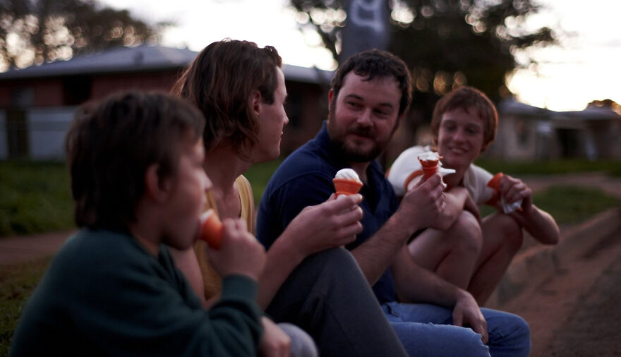 Four people sitting outdoors enjoying ice cream cones, a scene from movies based on true stories that feel impossible to believe.