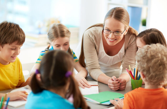 Teacher engaging with children in a classroom setting, illustrating the importance of recognizing symptoms that made cancer survivors see a doctor.
