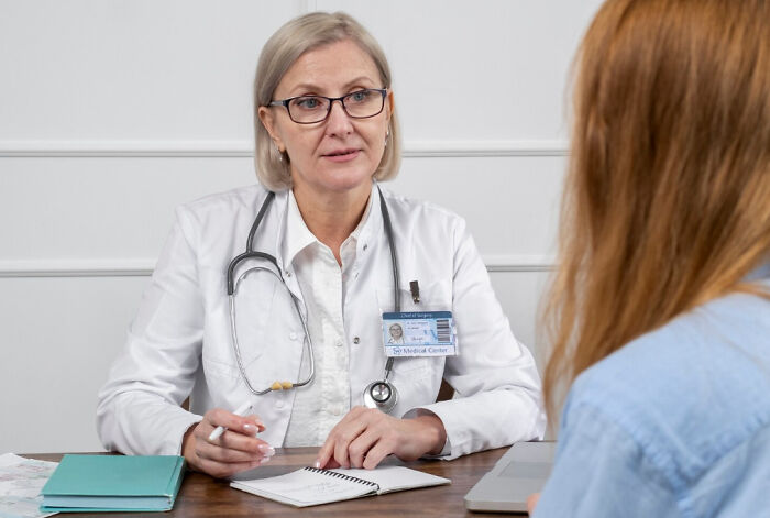 Female doctor with stethoscope consulting a patient, discussing unexpected symptoms that made cancer survivors see a doctor.