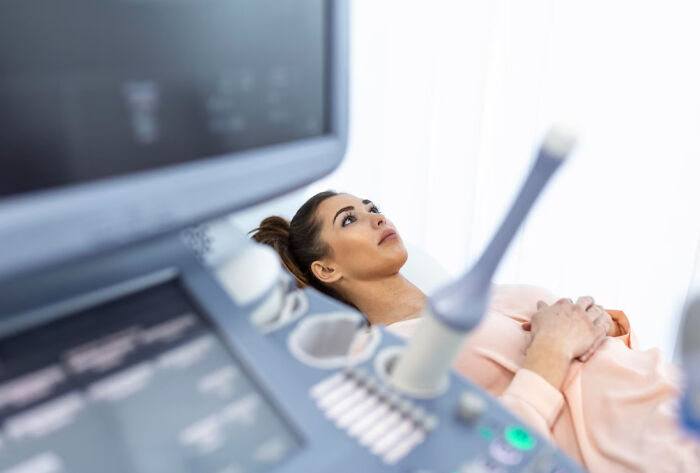 Woman lying on medical bed receiving ultrasound scan, highlighting cancer survivors unexpected symptoms and doctor visits