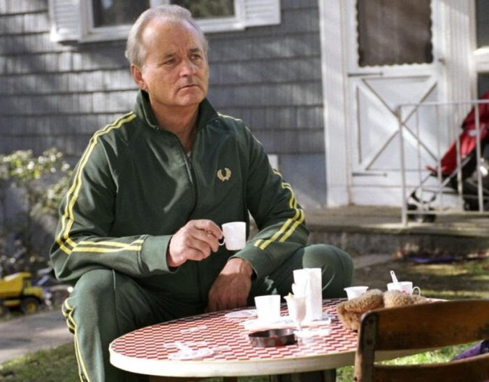 Man in green tracksuit sitting outdoors having coffee, illustrating unknown things about celebrities shared by people who met them.