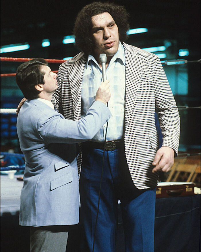 Interviewer holding microphone to tall celebrity in checkered jacket during event, illustrating unknown things about celebrities.
