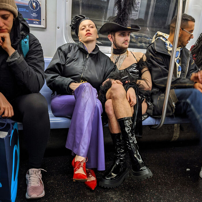Two fashionably dressed individuals wearing bold outfits and boots sit side by side on a NYC subway street portrait.