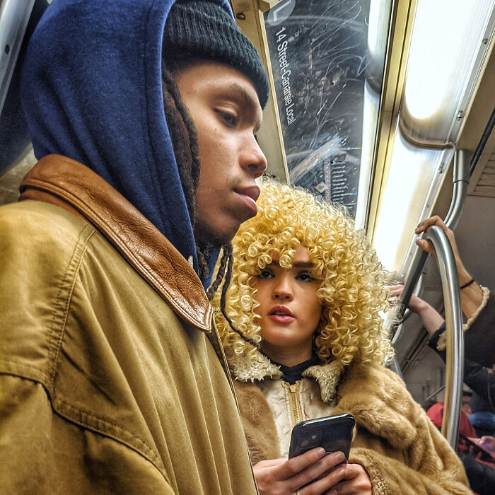 Two passengers captured in a street portrait on NYC’s subway, showcasing diverse urban life underground.