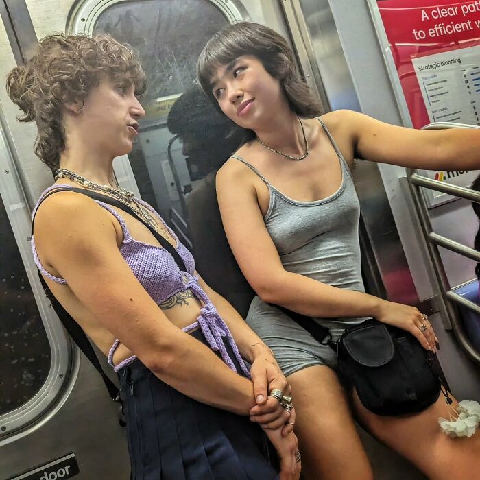 Two young women sitting and talking inside a NYC subway car, capturing street portraits and life underground.
