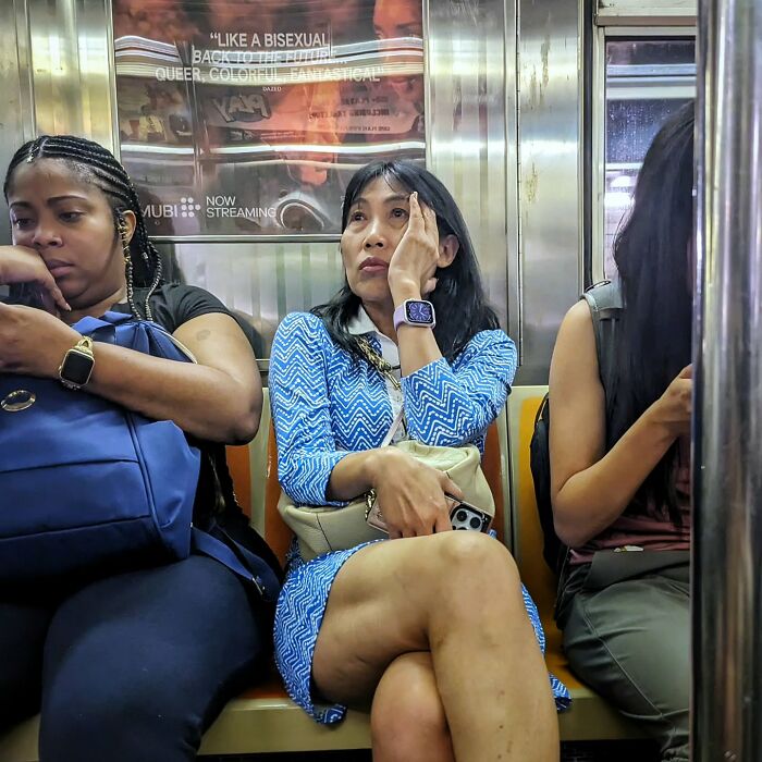 Three women seated inside a NYC subway car, captured in a street portrait showing diverse daily life underground.