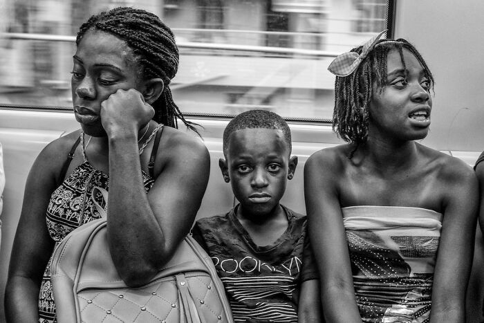 Three children sitting on public transport, captured in a candid moment showcasing childhood around the world.