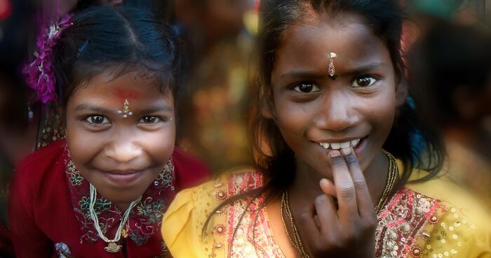 Two smiling girls in colorful traditional clothing, capturing the beauty of childhood around the world in a vibrant moment.