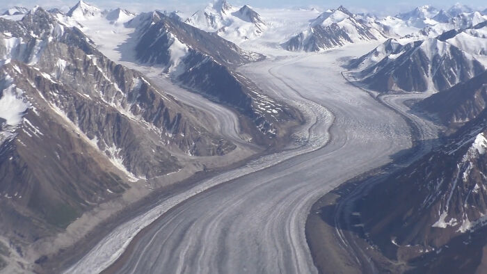 Wide aerial view of a massive glacier winding through snowy mountain peaks illustrating incredible weather records on Earth.
