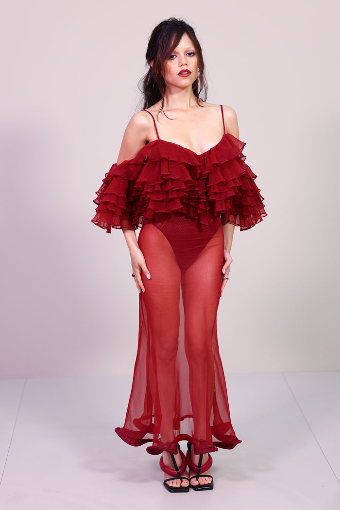 Model in a sheer red ruffled dress and black strappy heels showcasing a bold celebrity look at Paris Fashion Week 2025. Model in a sheer red ruffled dress and black strappy heels showcasing a bold celebrity look at Paris Fashion Week 2025.