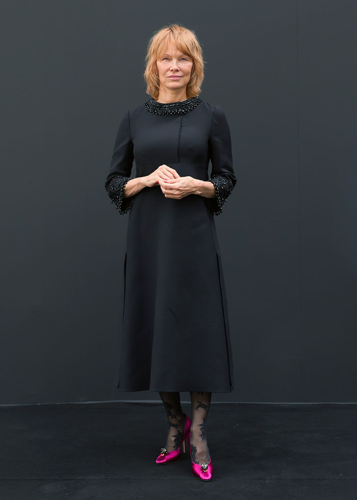 Woman in a black dress with embellished cuffs and collar paired with pink heels at Paris Fashion Week 2025 celebrity looks. Woman in a black dress with embellished cuffs and collar paired with pink heels at Paris Fashion Week 2025 celebrity looks.