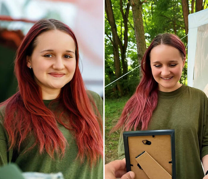 Young woman with long red hair smiling while looking at her own portrait captured by the photographer outdoors.