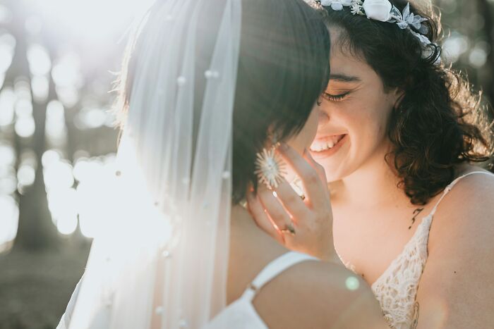 Two brides sharing an intimate moment outdoors, capturing a heartfelt secret that could change lives if revealed.