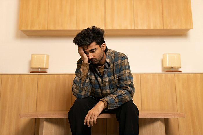 A distressed man sitting alone on a bench, reflecting on family conflict over a lady kissing another man.