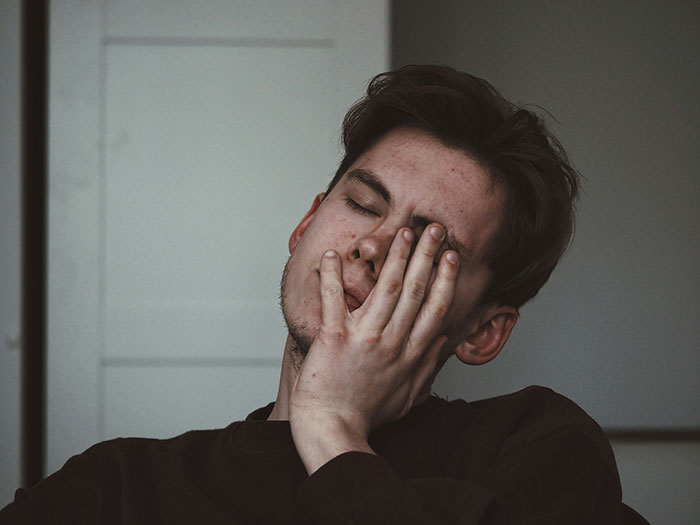 Young man with closed eyes, resting face on hand, conveying emotions related to rejection and dating after rejection. Young man with closed eyes, resting face on hand, conveying emotions related to rejection and dating after rejection.