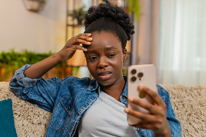Woman looking upset while holding smartphone, reacting to a surprising open marriage proposal video. Woman looking upset while holding smartphone, reacting to a surprising open marriage proposal video.