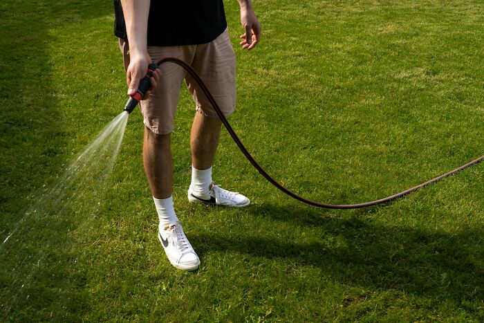 Person watering green grass with a hose, symbolizing nurturing and care, key relationship advice for couples.