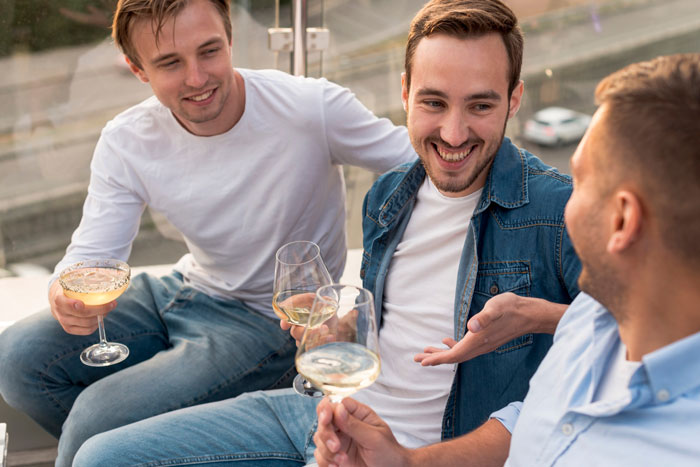 Three men enjoying drinks together outdoors, with one appearing as an annoying toxic friend to the photographer.