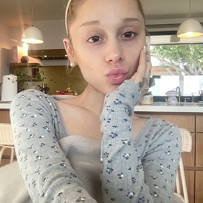 Ariana Grande with a dramatic new look, posing indoors, wearing a patterned grey top, facing fan backlash online. Ariana Grande with a dramatic new look, posing indoors, wearing a patterned grey top, facing fan backlash online.