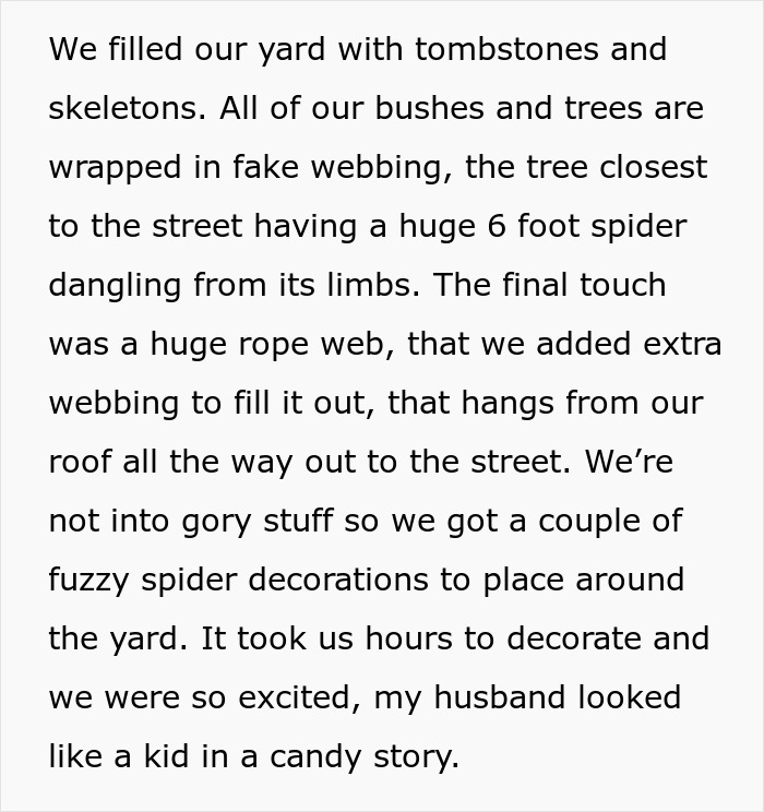 Halloween yard decorations with tombstones, skeletons, fake webbing, and large spider hanging from tree limbs.