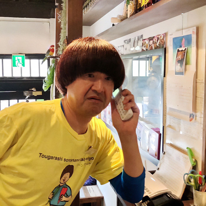 Man in yellow shirt talking on phone inside a Japanese restaurant amid tourists kicked out over revealing sports attire debate