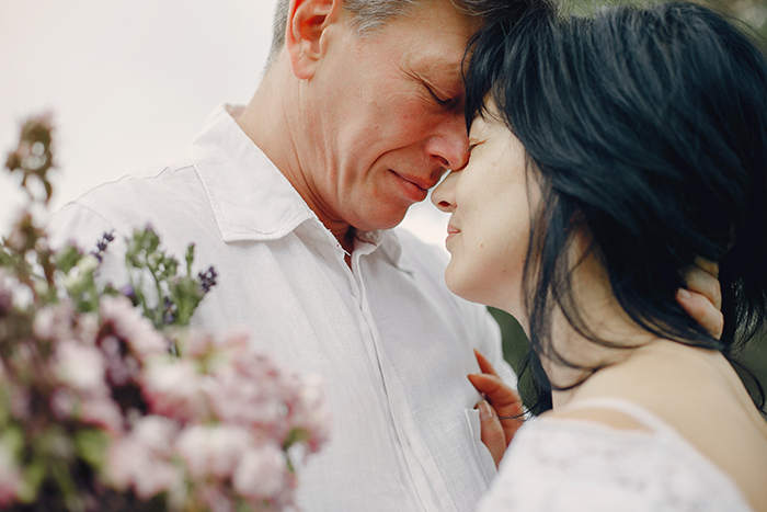 Couple sharing a tender moment outdoors with flowers nearby, reflecting emotions of stepdaughters disown stepmother drama.