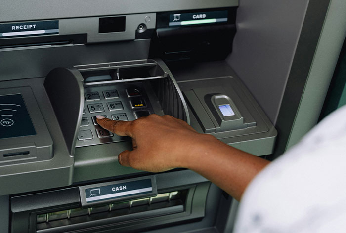 Person entering PIN at an ATM keypad, illustrating a common loophole discovery in automated cash machines.