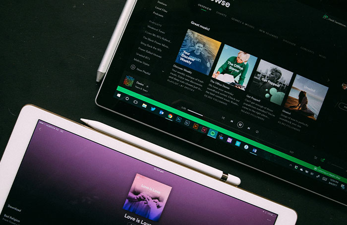 Two tablets displaying music apps with styluses placed on a dark surface, illustrating digital loopholes in app usage.