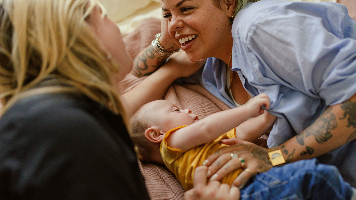 Couple and baby bonding warmly on a bed, representing IVF and family connection moments with loving smiles.