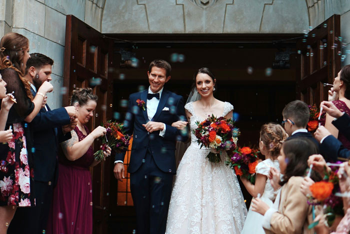 Bride and groom exiting church during wedding ceremony, surrounded by guests celebrating with flowers and confetti. Bride and groom exiting church during wedding ceremony, surrounded by guests celebrating with flowers and confetti.