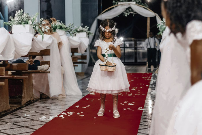 Young flower girl in white dress walking down wedding aisle, highlighting child-free wedding plans and travel costs. Young flower girl in white dress walking down wedding aisle, highlighting child-free wedding plans and travel costs.