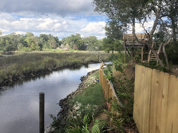 Riverside land with wooden fence and treehouse illustrating neighbors trying to steal part of her land conflict.