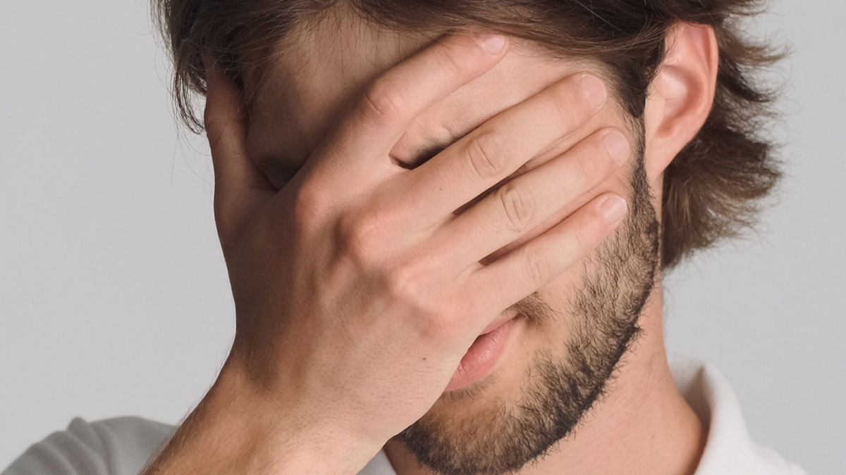 Man covering face with hand showing frustration dealing with worst employees at work according to bosses