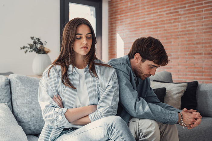 Young couple sitting apart on a sofa looking upset, reflecting boyfriend mother family expectations conflict at home Young couple sitting apart on a sofa looking upset, reflecting boyfriend mother family expectations conflict at home