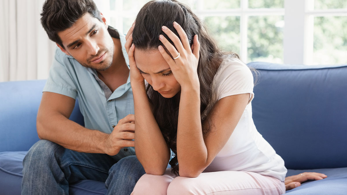 Man comforting upset woman on a couch, shocked and horrified after Thanksgiving family conflict theory discussion.