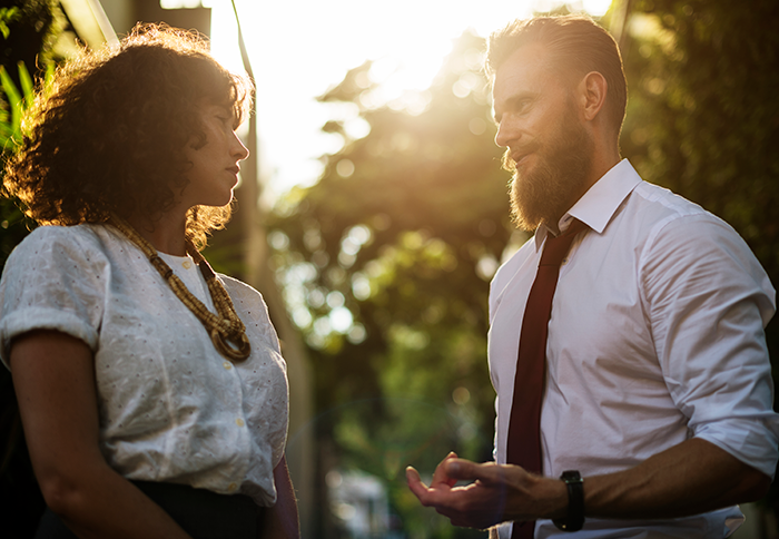 Man and woman engaged in a serious outdoor conversation, representing an obnoxious dinner guest and dreadful husband scenario. Man and woman engaged in a serious outdoor conversation, representing an obnoxious dinner guest and dreadful husband scenario.